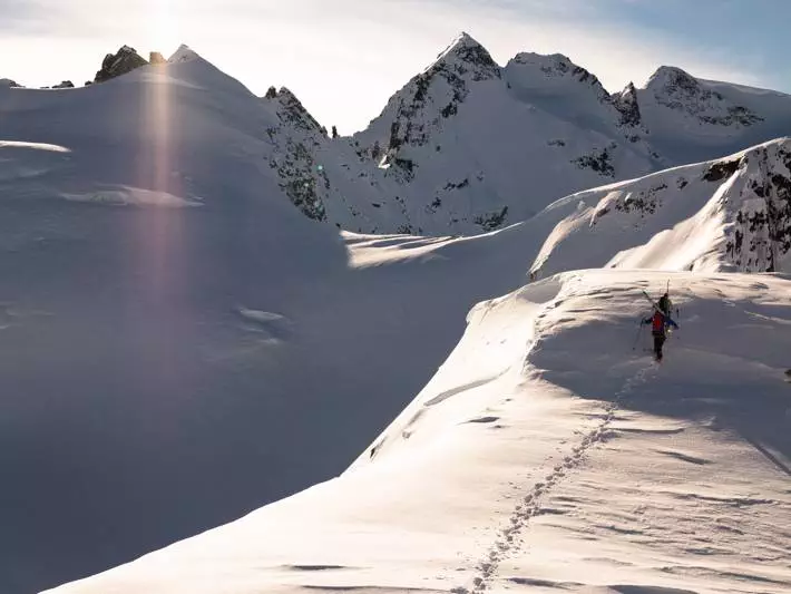 A skier summiting a snow-covered mountain in Canada.
