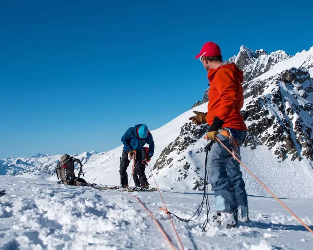 Two men hooking up crevasse rescue system